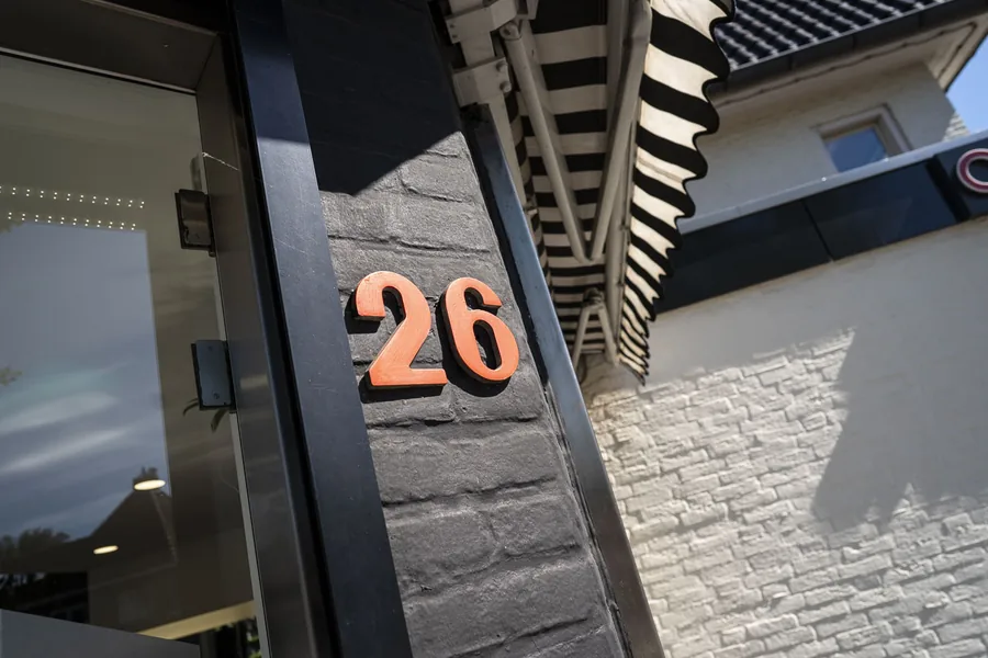 Het koperen huisnummer 26 op de zwarte gevel aan de Parkstraat