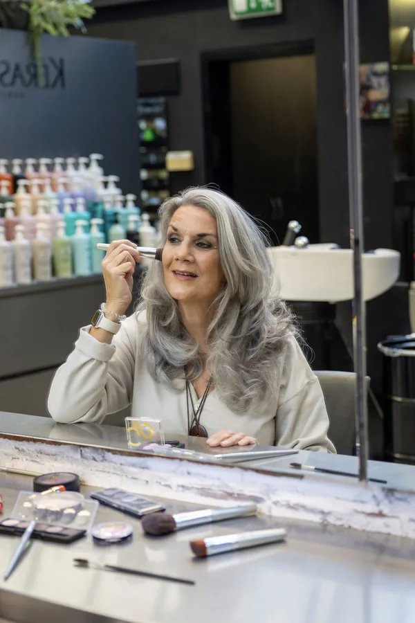 Linda in de spiegel van de salon, met een make-upkwast