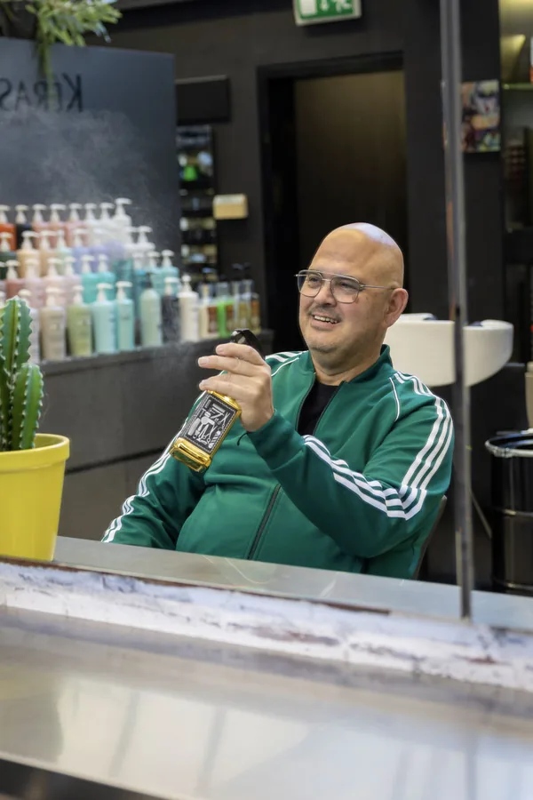 Raymond in de spiegel van de salon, met een sprayflacon in de hand