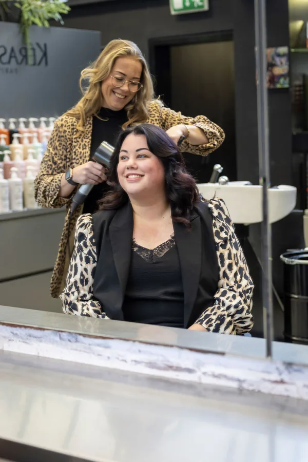 Romy in de spiegel van de salon, terwijl haar haar wordt geföhnd