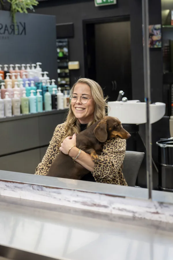 Sarah-Ann in de spiegel van de salon, met een teckel op schoot