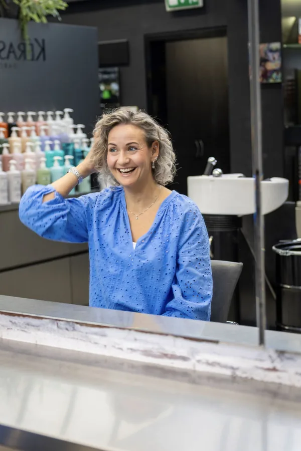Stefanie in de spiegel van de salon, met een hand door het haar